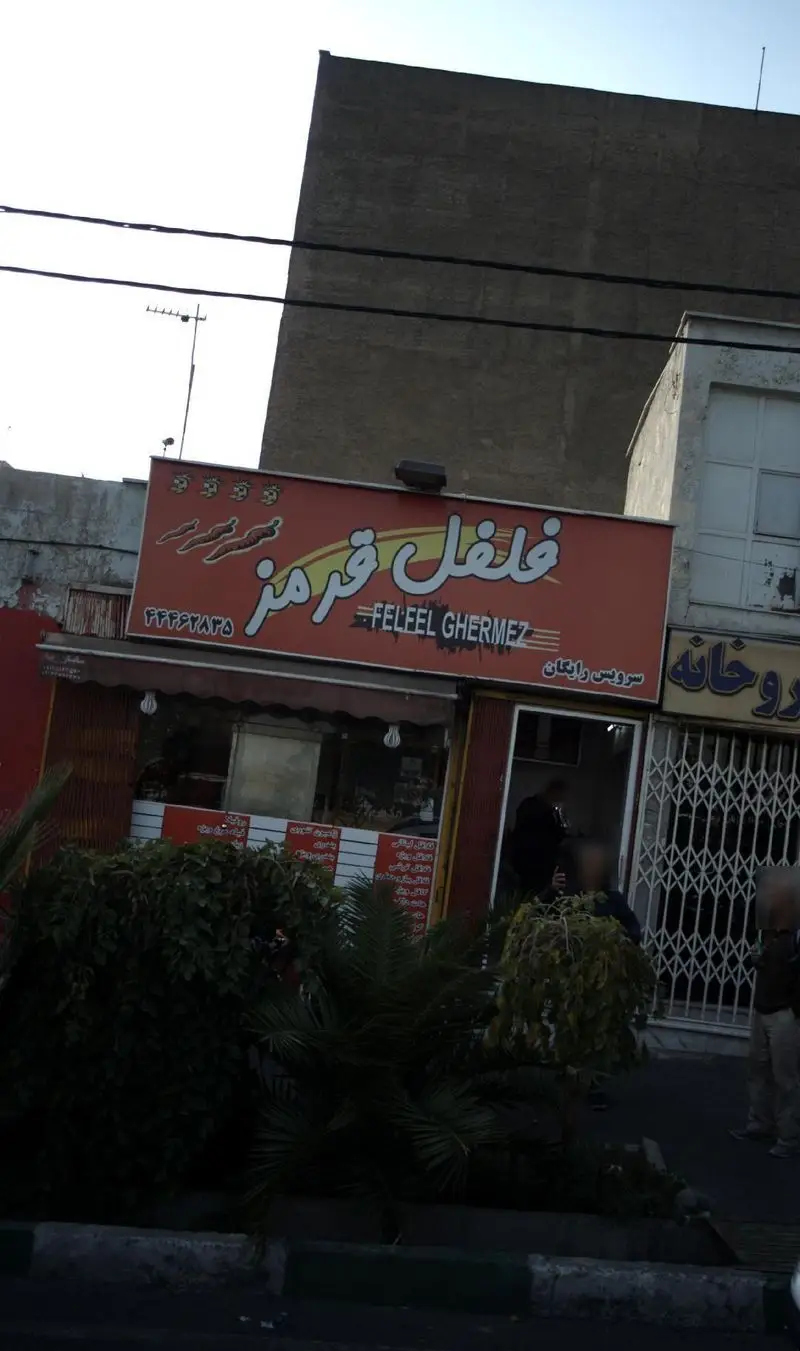 نمای جلوی ساندویچی فلفل قرمز، تابلوی قرمز رنگ با نام 'فلفل قرمز' (Felfeel Ghermez)، شماره تلفن ۶۶۶۴۷۸۲۵ و امکان ارسال رایگان.