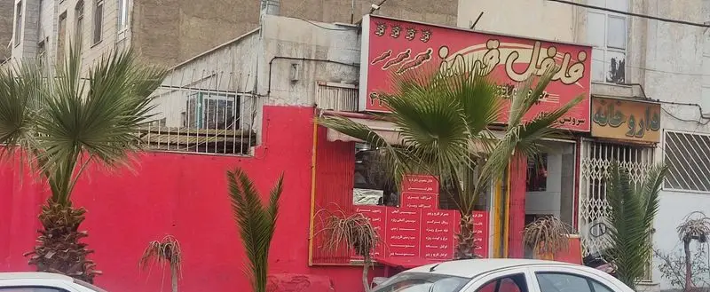 نمای بیرونی جذاب فست فود فلفل قرمز با تابلوی روشن و دیوار قرمز، مزین به درختان نخل در جلوی ورودی.