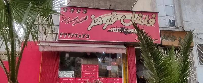 نمای بیرونی کسب‌وکار فلفل قرمز، اغذیه فروشی با تابلوی صورتی، شامل نام 'فلفل قرمز'، تصویر فلفل چیلی و شماره تلفن ۴۴۴۶۲۸۳۵.