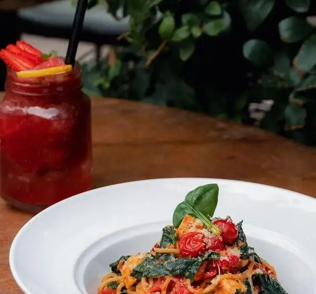 اسپاگتی لذیذ با سس گوجه فرنگی، تکه‌های مرغ، سبزیجات تازه و پنیر پارمزان در کافه رستوران دایموند، با اسموتی توت فرنگی.