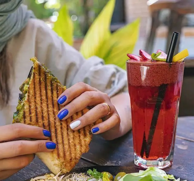 مشتری در کافه رستوران دایموند در حال لذت بردن از ساندویچ گریل و اسموتی توت‌فرنگی تازه در محیطی آرام و دلنشین.