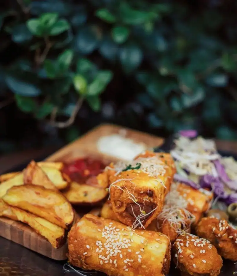 بشقاب جذاب فینگرفود شامل رول‌های سوخاری کنجدی و سیب زمینی وجز در کافه رستوران دایموند با چاشنی‌های خوش‌طعم.