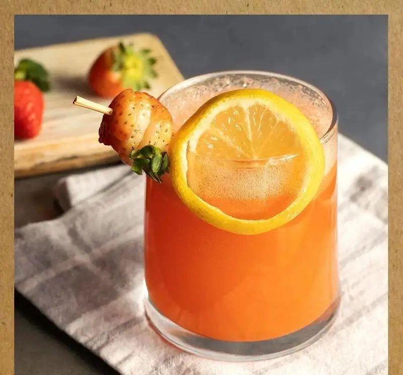 نوشیدنی خنک و تازه پرتقال با تزیین لیمو و توت فرنگی، ایده‌آل در خانه فرهنگ و هنر سرهنگ برای لذت بردن از طعم‌های طبیعی و سلامتی.