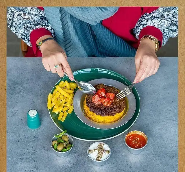 تصویری از غذای محبوب ته چین با سیب زمینی سرخ کرده، زیتون و ماست در کافه رستوران خانه فرهنگ و هنر سرهنگ. یک وعده غذایی لذیذ.