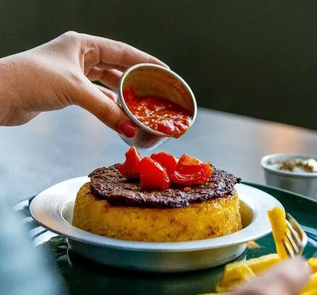 دستی سس قرمز خوشرنگ را روی برنج زرد قالبی، کباب و گوجه‌های تازه می‌ریزد، تجربه‌ای لذیذ در خانه فرهنگ و هنر سرهنگ.