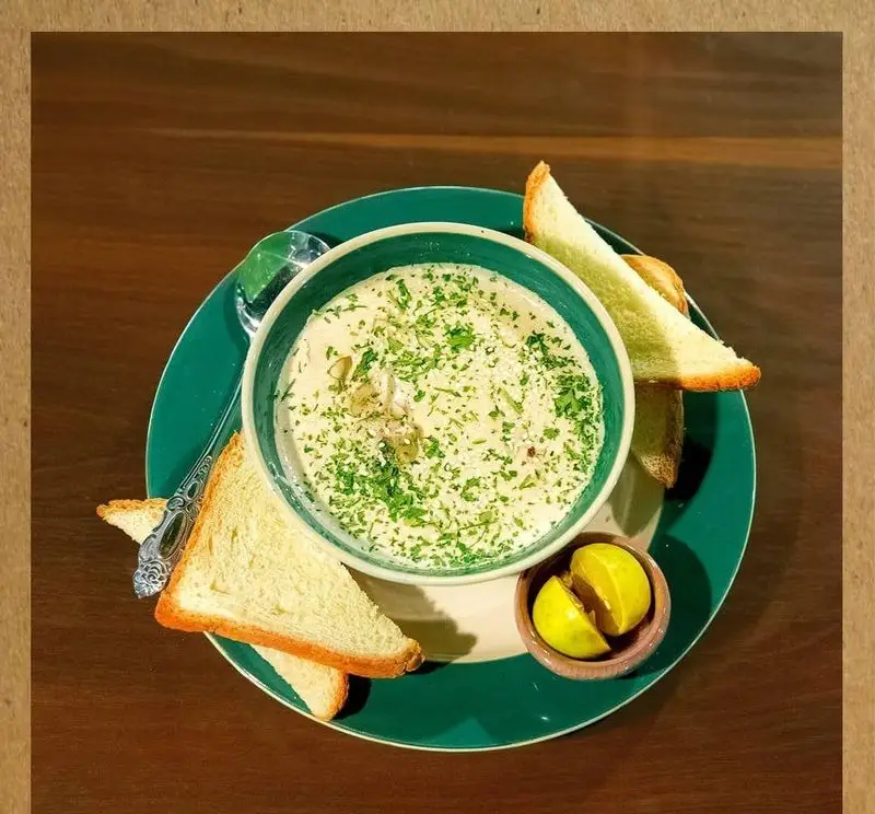 سوپ خامه‌ای دلپذیر با جعفری خرد شده و تکه‌های قارچ، همراه نان تست برشته و لیمو. طعمی خاص از خانه فرهنگ و هنر سرهنگ.