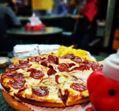 تصویری جذاب از پیتزا پپرونی داغ و لذیذ فست فود مستر برگر به همراه سیب زمینی سرخ کرده. مکانی عالی برای تجربه طعم بی‌نظیر غذاها.