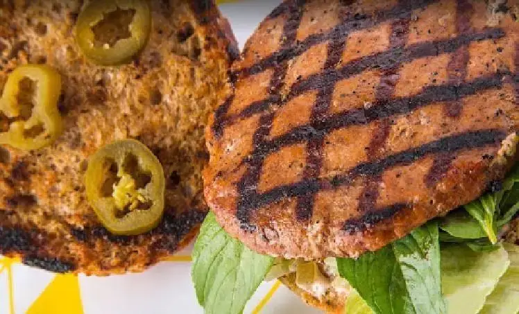 یک برگر گریل شده ویژه از فست فود فریکادل با نان برشته سبوس‌دار، پتی گوشت آبدار، کاهو ترد و حلقه‌های فلفل هالوپینو.