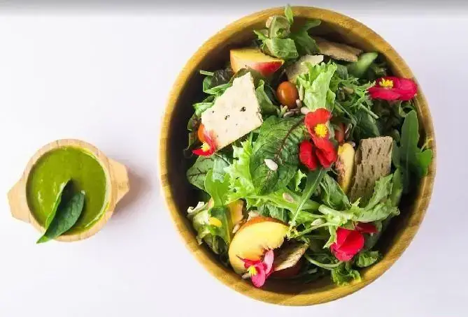 سالاد میوه و سبزیجات تازه و اشتهاآور فست فود فریکادل شامل کاهو، هلو، گوجه گیلاسی، کراکر و سس سبز رژیمی.