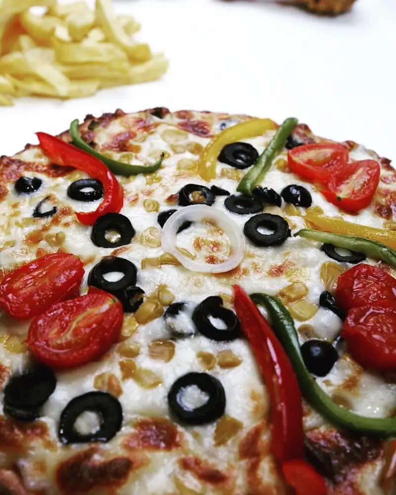 پیتزای تنوری خوشمزه و پرپنیر از پیتزا تنوری پاروت با زیتون سیاه، فلفل دلمه‌ای‌های رنگی، گوجه گیلاسی و حلقه‌های پیاز.