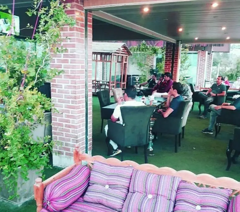 فضای باز و دلنشین کافه رستوران ایرانی باراد با چیدمان سنتی، میز و قلیان، مناسب دورهمی دوستانه و خانوادگی.