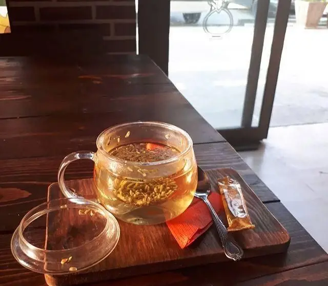 تصویری از یک فنجان دمنوش یا چای گیاهی گرم و دلنشین در رستوران ایرانی باراد. با میز چوبی زیبا و محیطی آرام برای مشتریان.