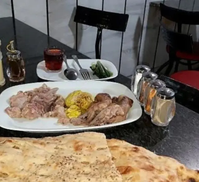 تصویری از میز غذا در طباخی و سیرابی سید: کله پاچه، گوشت، سیرابی و پرنده پخته با نان سنگک داغ، مناسب برای صبحانه و وعده های اصلی.