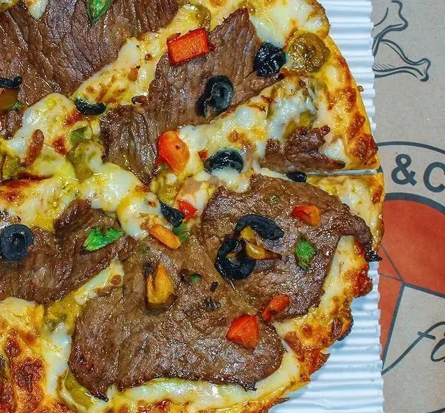 پیتزا استیک خوشمزه از فینا فود با تکه‌های گوشت، پنیر فراوان، فلفل دلمه‌ای رنگی و زیتون. ایده‌آل برای سفارش آنلاین.