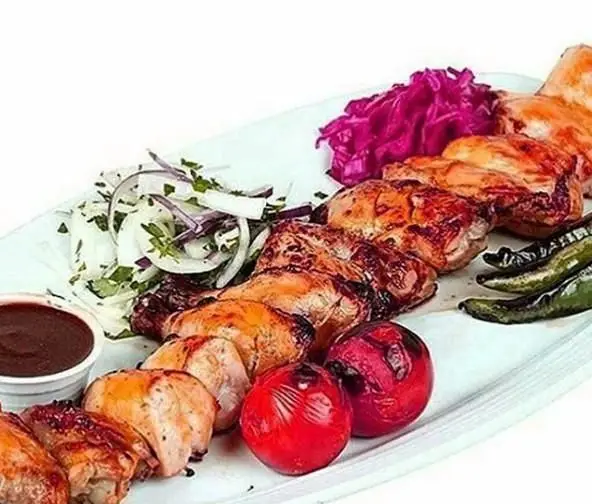 کباب مرغ و گوشت آبدار رستوران توچال کباب با پیاز جعفری، کلم قرمز، گوجه و فلفل کبابی و سس مخصوص در بشقاب سفید.