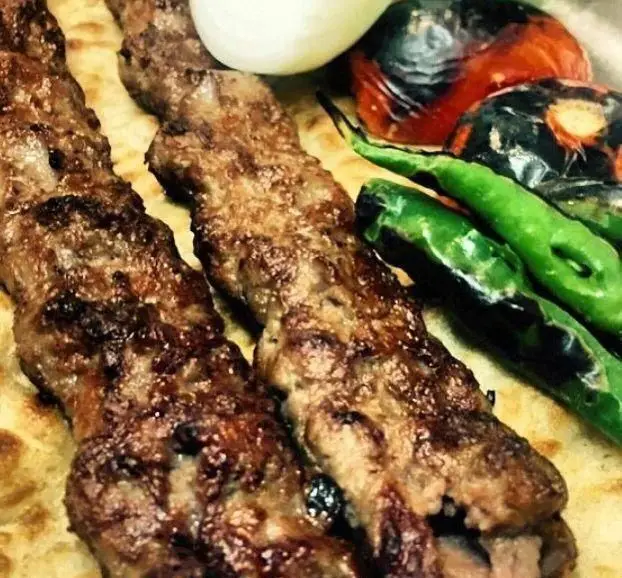 نمایی نزدیک از کباب کوبیده رستوران توچال کباب روی نان تازه، همراه با گوجه و فلفل کبابی، تجربه‌ای بی‌نظیر از غذای اصیل ایرانی.