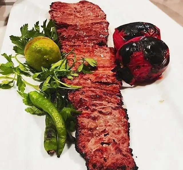 کباب برگ لذیذ رستوران توچال کباب با گوجه کبابی، لیمو ترش تازه، جعفری و فلفل سبز، یک تجربه غذای ایرانی اصیل.