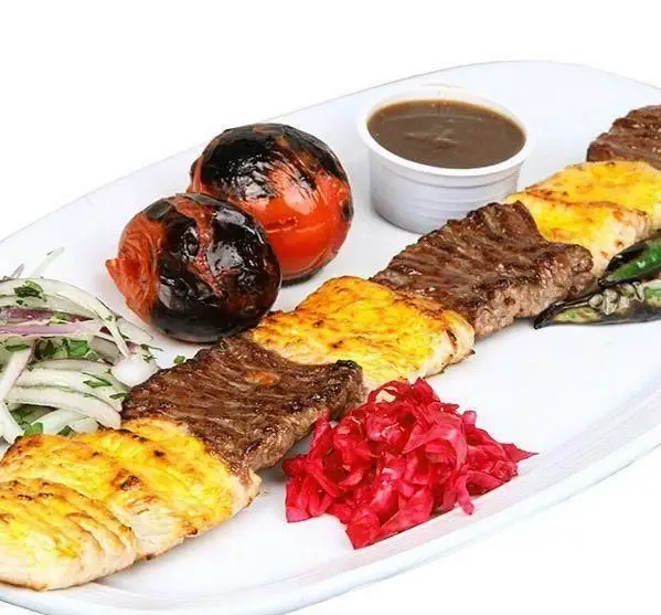 یک بشقاب کباب میکس لذیذ از رستوران توچال کباب، شامل کباب برگ، جوجه کباب، گوجه کبابی، پیاز، فلفل و مخلفات تازه ایرانی.