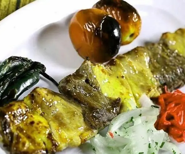 کباب ایرانی لذیذ رستوران توچال، شامل جوجه کباب و سبزیجات گریل شده (فلفل و گوجه)، همراه پیاز و مخلفات تازه. غذای اصیل و خوش طعم.