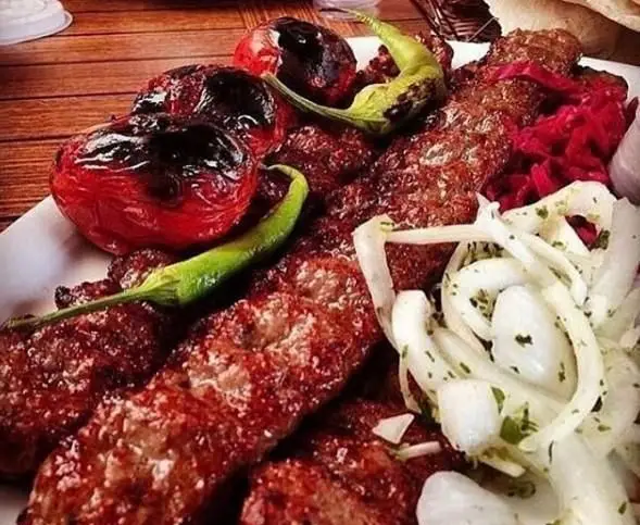 تصویری از یک پرس کباب کوبیده لذیذ و خوش طعم رستوران توچال کباب، همراه با گوجه کبابی، فلفل کبابی و پیاز تازه، غذای سنتی ایرانی.