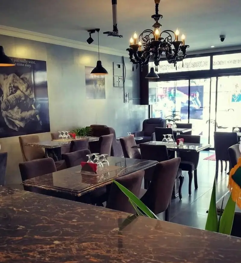 تصویر فضای داخلی شیک رستوران ایتالیایی پی نو با میزهای مرمری، صندلی‌های مخملی تیره و لوستر زیبا برای یک وعده غذایی دلپذیر.