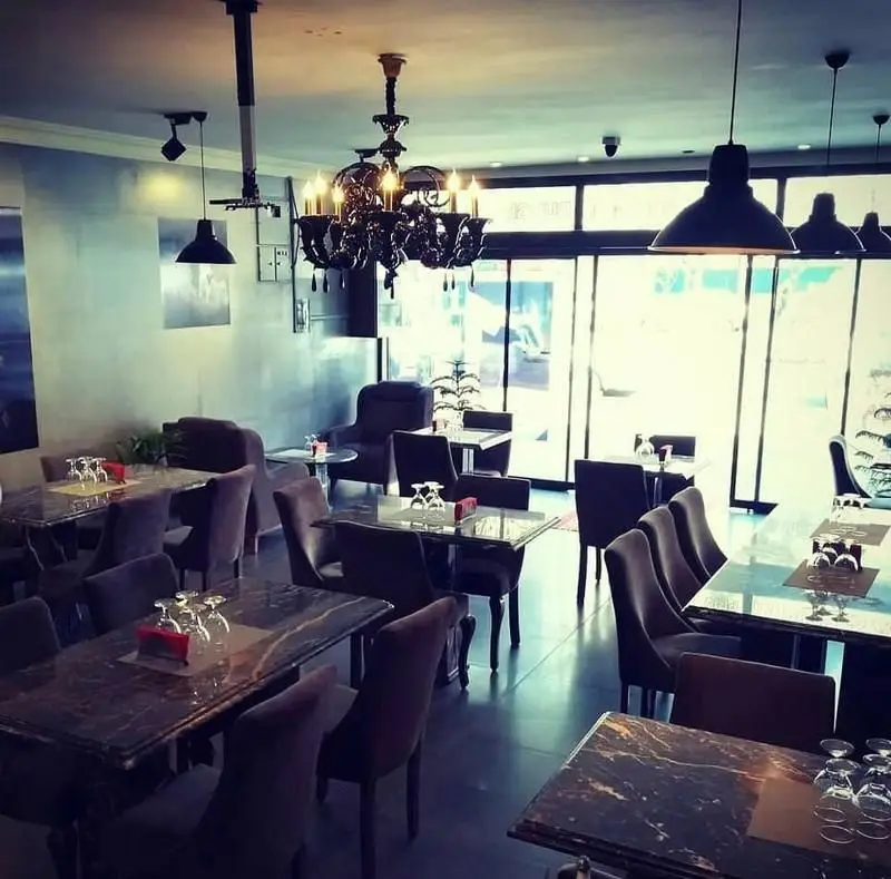 فضای داخلی شیک و دنج رستوران ایتالیایی پی نو، با میز و صندلی‌های مدرن، لوستر زیبا و نورپردازی دلنشین برای تجربه‌ای لذت‌بخش.