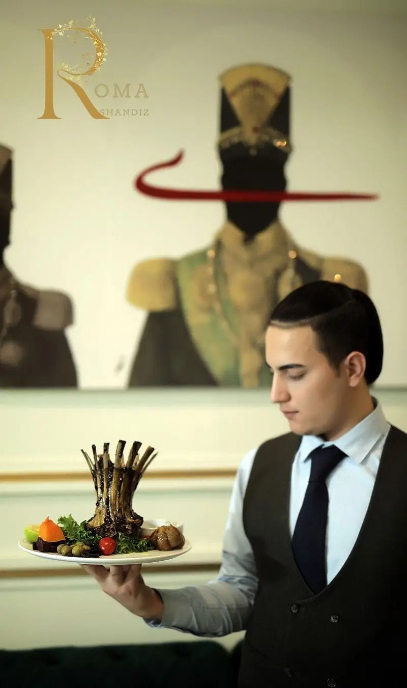 نمایی زیبا از گارسون رستوران شاندیز روما در حال ارائه بشقاب شیشلیک ممتاز و خوش‌طعم، نمادی از کیفیت و سرویس لوکس.