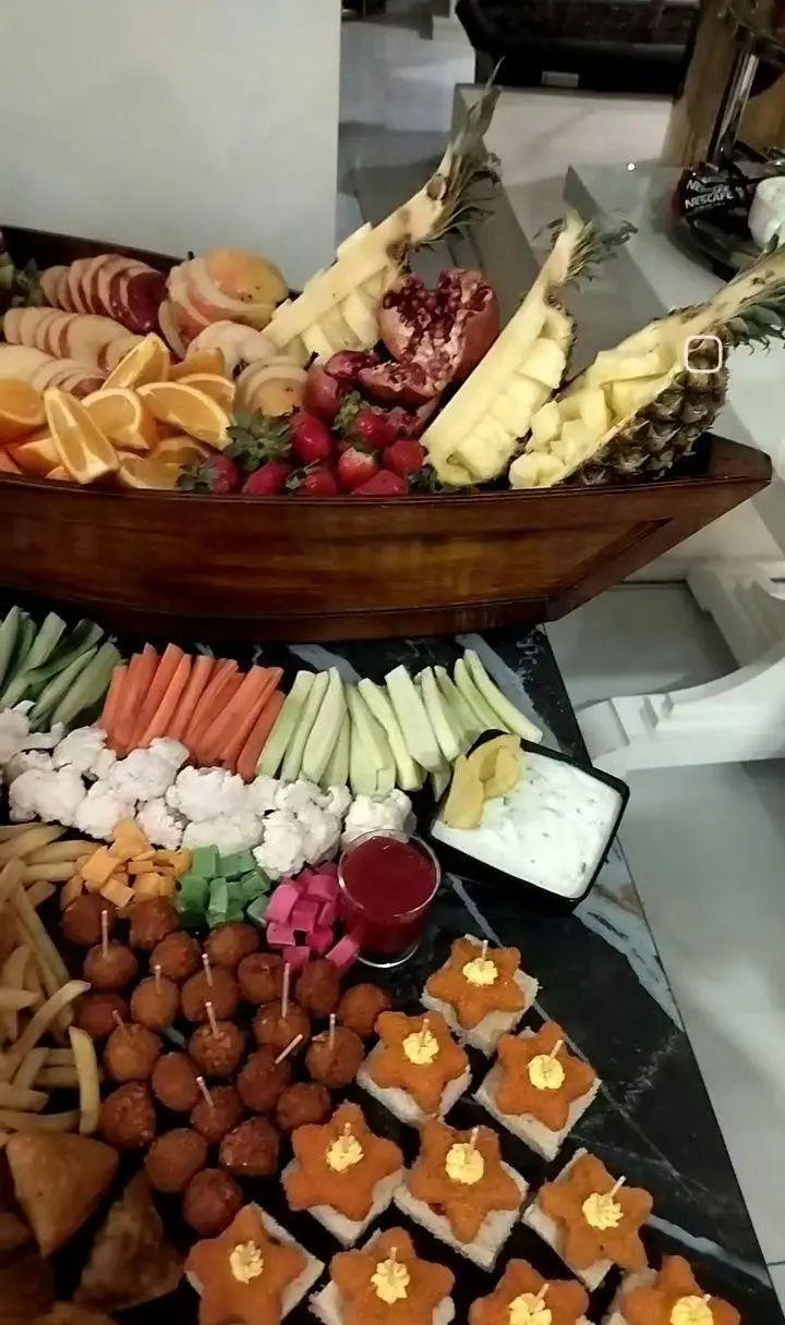 پذیرایی شاندیز روما: سینی میوه آرایی مجلل (آناناس، انار، پرتقال، توت فرنگی، سیب)، فینگر فود متنوع (سبزیجات تازه، مزه، کاناپه، سیب زمینی سرخ کرده، اسنک) برای مهمانی و مراسم.