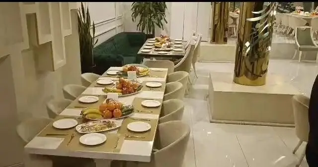 فضای داخلی مجلل رستوران شاندیز روما: میزهای چیده شده با میوه و غذا، دکوراسیون لوکس با مبلمان راحت و ستون‌های طلایی، آماده پذیرایی از میهمانان عزیز.