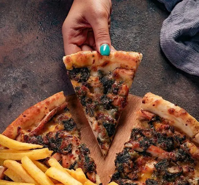 دست در حال برداشتن برش پیتزای خوشمزه از رستوران زنجیره‌ای شیلا شعبه سهروردی شمالی، همراه با سیب‌زمینی سرخ کرده.