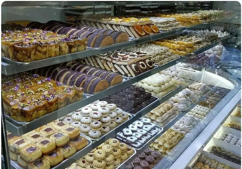 تصویری از ویترین خیره‌کننده قنادی نوبری با مجموعه‌ای متنوع از شیرینی‌های سنتی و مدرن، کیک، کلوچه و دسر تازه و خوش‌رنگ.