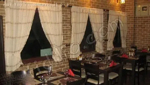 نمای داخلی رستوران ایتالیایی بیسترو با دکوراسیون زیبای آجری، میزهای چوبی چیده شده با ظروف و پرده‌های شیک.