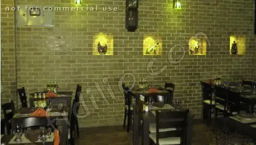 نمایی از فضای داخلی رستوران ایتالیایی بیسترو با دیوارهای آجری، نورپردازی خاص و میز و صندلی‌های چوبی برای تجربه غذایی دلپذیر.