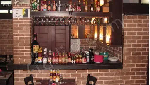 دکوراسیون داخلی رستوران ایتالیایی بیسترو با دیوارهای آجری، بار مجهز به انواع نوشیدنی و سس، و میز و صندلی‌های شیک برای مشتریان.