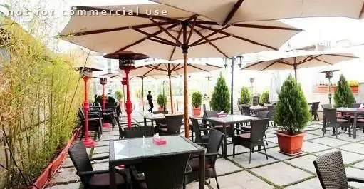 نمایی از فضای باز رستوران ستارگان شاندیز فرمانیه با چترهای بزرگ، میز و صندلی‌های شیک و بخاری‌های فضای باز، مکانی دلنشین برای مشتریان.