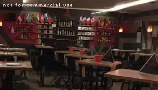 محیط داخلی رستوران پیتزا لاوین با نورپردازی گرم، میز و صندلی‌های چوبی، قفسه‌های پر از بطری و دکوراسیون پرچم کشورهای مختلف.