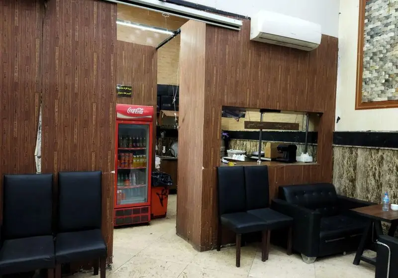 دکوراسیون داخلی کافه عربی صوفیا با دیوارپوش چوبی، صندلی‌های راحت مشکی، یخچال نوشیدنی و پیشخوان آماده‌سازی سفارشات.