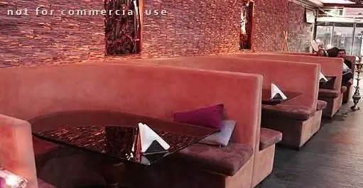 فضای داخلی کافه رستوران دل فارو با غرفه های نشیمن راحت به رنگ صورتی و میزهای شیک، مناسب برای دورهمی و استراحت.