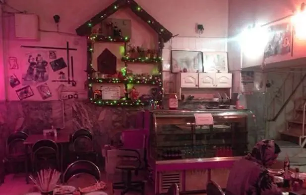 فضای داخلی دنج و دلنشین رستوران آلونک، با دکوراسیون چوبی به شکل خانه، چراغ‌های تزئینی و میز و صندلی‌های راحت.