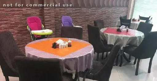 محیط داخلی رستوران با میزهای گرد آماده سرو غذا، صندلی های تیره و دکوراسیون دیواری طرحدار، مناسب خانواده در اکبرجوجه ملل.