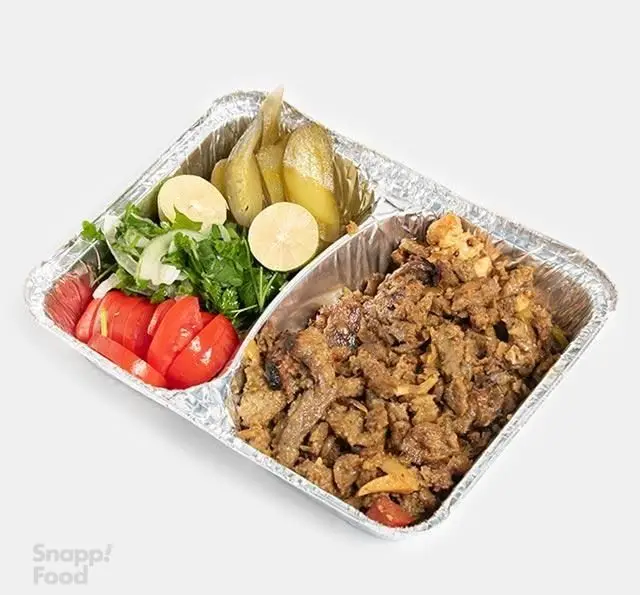 خوراک گوشت لذیذ بارو در ظرف آلومینیومی، همراه با سالاد تازه شامل گوجه، سبزی، پیاز، لیمو و خیارشور. غذای ایرانی و بیرون بر.