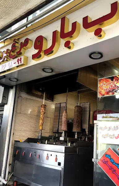 نمای بیرونی فست فود بارو با دستگاه‌های شاورما و دونر کباب مرغ و گوشت تازه، آماده سرو غذاهای لذیذ و ساندویچ