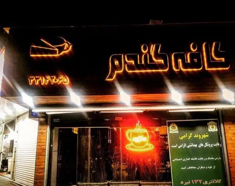 تصویر نمای شب کافه گندم با تابلو نئونی درخشان و لوگوی فنجان قهوه، همراه با شماره تماس 3314295 و پیام رعایت پروتکل‌های بهداشتی.