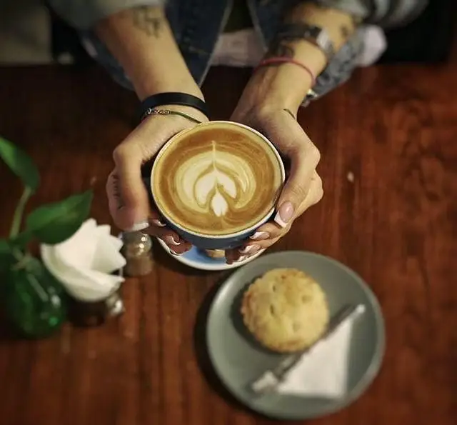 تجربه نوشیدن لاته آرت زیبا با شیرینی در فضای دلپذیر کافه مان و رو، مکانی عالی برای دورهمی‌ها و استراحت.