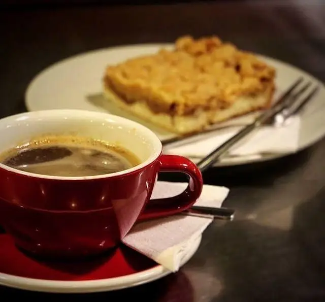 قهوه تازه‌دم در فنجان قرمز و کیک خوشمزه با روکش ترد در کافه مان و رو، بهترین انتخاب برای دورهمی‌ها و اوقات دلنشین.