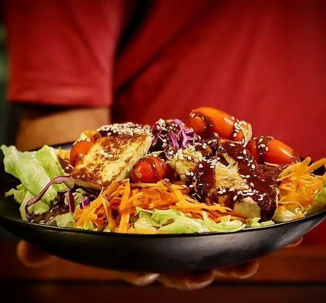 سالاد ویژه کافه مان و رو شامل کاهو، هویج، گوجه گیلاسی، تکه‌های مرغ و پنیر گریل شده با سس و کنجد، غذای سالم و خوشمزه.