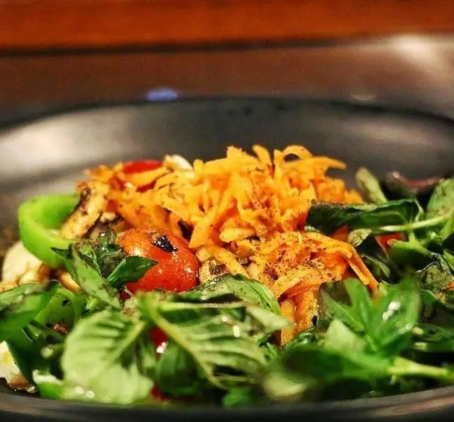 سالاد رژیمی و سالم کافه مان و رو با ترکیب دلنشین سبزیجات تازه، گوجه، فلفل و هویج در یک ظرف تیره رنگ، مناسب برای ناهار.