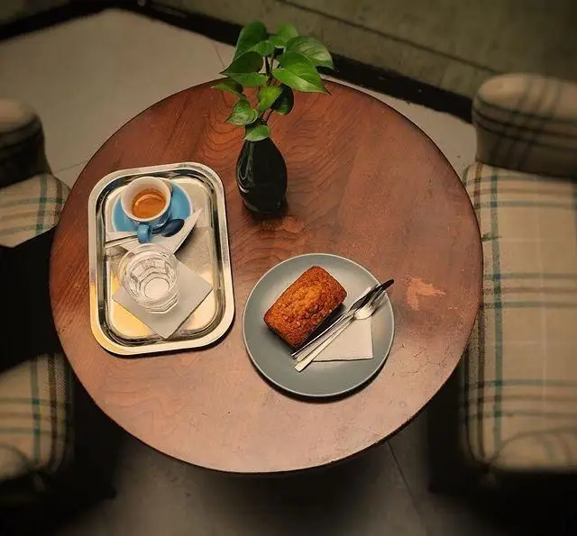 میز قهوه در کافه مان و رو: سینی با اسپرسو، آب و کیک خوش طعم. لحظاتی دلپذیر در فضایی دنج و آرام برای شما.