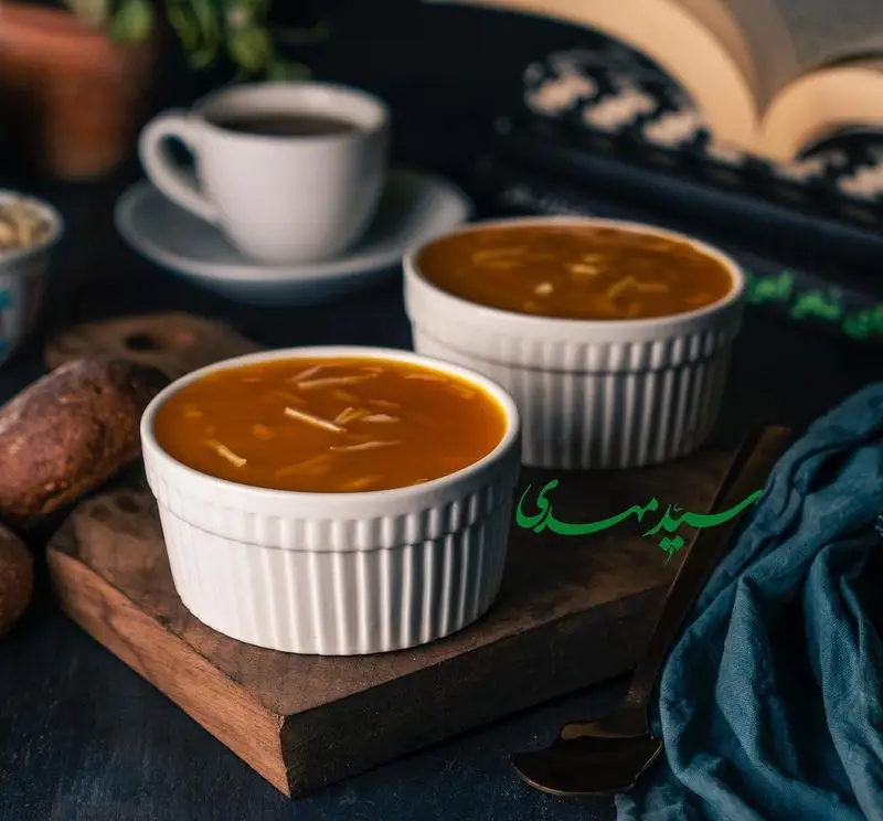 دو کاسه حلیم و آش سنتی سید مهدی، غذایی گرم و دلپذیر برای صبحانه یا افطار، همراه با فنجان چای و کتاب در یک محیط آرام و دلنشین.