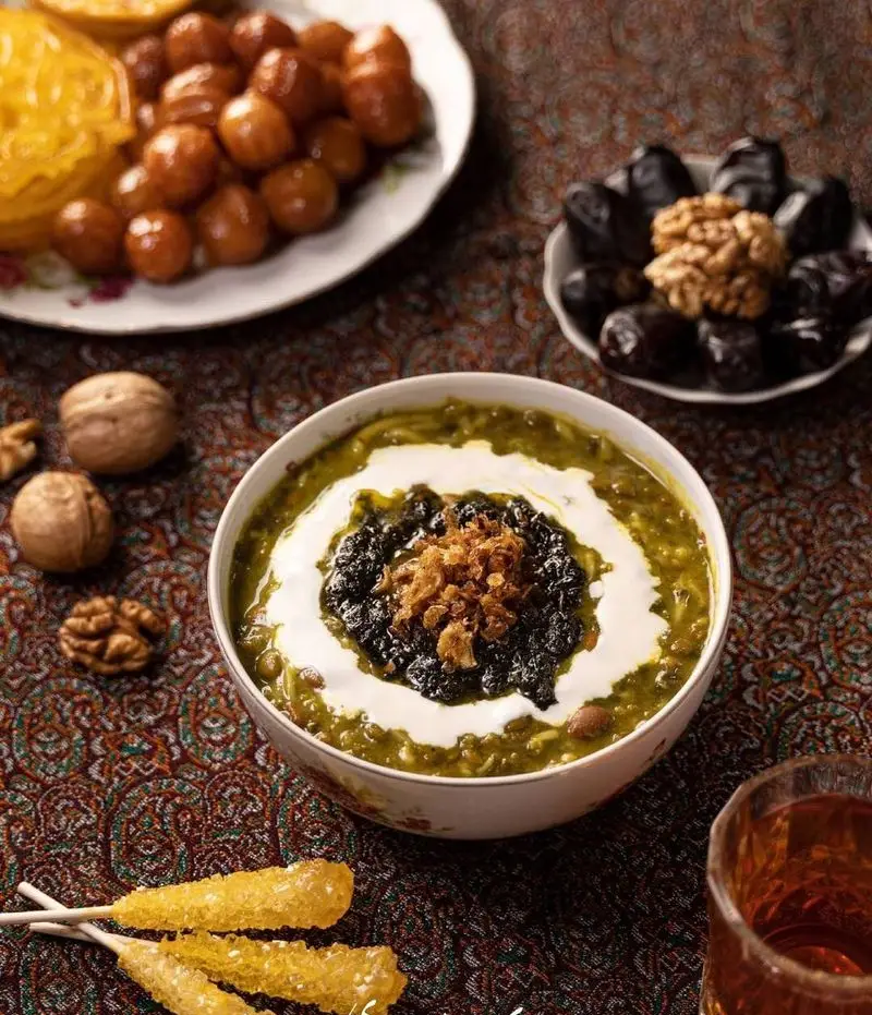 آش سبز سنتی "حلیم و آش سید مهدی" با تزیین کشک، نعناع و پیاز داغ، به همراه زولبیا، بامیه، خرما، گردو و چای؛ سفره‌ای دلپذیر و کامل برای افطار.